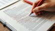© MOMO - A red pen marking corrections on a printed manuscript at a desk workspace.