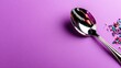 © svastix - A polished silver spoon rests elegantly on a vibrant purple backdrop, complemented by colorful sprinkles, evoking a sense of joy and creativity in the kitchen narrative.