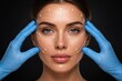 © Olga Ко - Concept of plastic surgery and cosmetology. Hands of doctor in blue medical gloves touching beautiful woman's face with white surgical markup lines. Dark background