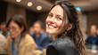 © Shahazadi - Smiling young professional woman looking back during a corporate conference session