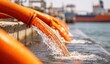 © amat - Orange pipes discharge water into a body of water near an industrial area.