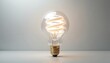 © Viktor - Single white spiral light bulb glows warmly. Clear glass surrounds a swirled filament. Golden metal base connects to electric power. Modern lighting innovation idea.
