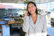 © Ranta Images - A smiling Asian woman from Thai Isan talking on a smartphone in a professional cafe.