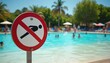 © Viktor - No diving allowed sign near pool. People swim in water on sunny day. Summer vacation at hotel resort with lounge chairs and umbrellas in background.