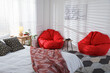 © New Africa - Red bean bag chairs and wooden table with game controllers in bedroom. Interior design