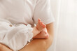 © Roman - Close-up of tiny newborn baby feet held by mother, tender skin and white cotton clothes.