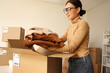 © Pixel-Shot - Female Asian seller packing sheepskin coat in warehouse store