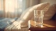 © NovaVision - Glass of clear water on a wooden table bathed in warm morning sunlight