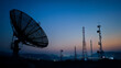 © Alexander - Satellite dish and telecommunication towers silhouetted at dusk, wireless network infrastructure scene with antennas, evening sky, data transmission, broadcasting and modern connec