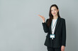 © gohan - グレーバックの手のひらを広げるポーズをする若いスーツの日本人女性