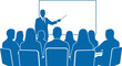 © hamza - Professional business leader pointing to a blank screen while delivering an important presentation to a group of attentive office employees