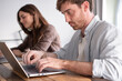 © luciano - Focused Man and Woman Working Together on Laptops in Casual Home Office Environment