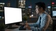 © FANGWORLD - Asian businessman working late at night at his desk in a modern office, illuminated by the glow of his computer screen and city lights outside
