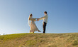 © Anna - Beautiful Ukrainian newlyweds in love, standing barefoot on the grass against a cloudless sky, looking tenderly at each other. cheerful bride in wreath and groom, happy moment, walking in park.