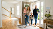 © Trendy Graphics - A family of four walking into their new home excitedly entering through the front door with a child being carried