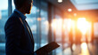 © Kateryna - Silhouette of a figure holding a clipboard standing in a bright corporate lobby with softly defocused office interior, corporate professional, business casual, confident employee