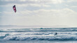 © Travel 'n' Lifestyle - View of a kitesurfer riding over choppy waves with a pink kite under a cloudy sky in Sardinia, Italy.