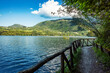 © Travel 'n' Lifestyle - View of Bacino di Suviana with its serene water and a rustic wooden fence path under a blue sky in Metropolitan City of Bologna, Emilia-Romagna, Italy.