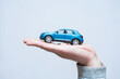 © vadish - Small scale model of a modern blue suv car resting on a man palm. Concept car buying, auto insurance protection, vehicle loan accessibility and transportation gifts.
