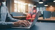 © Frendev - Person typing on a laptop with red cyber alert icons floating above the screen. Concept of malware warning, phishing risk, and online threat detection