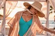 © starush - Woman in resort wear and sunhat at beach cabana wearing turquoise swimsuit at sunset