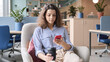 © insta_photos - Young indian female student sitting on chair in modern creative space using cell smartphone learning app. Latin teenager girl holding coffee reading ebook surfing social media texting messaging.