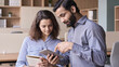© insta_photos - Diverse friendly coworkers colleagues indian male manager and latin female employee talking in office space using tablet device. Effective management, teaching and mentoring new employee concept.