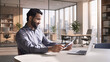 © insta_photos - Smiling indian business man employee working on laptop looking at document at home office. Male ethnic professional teacher reading paper, employer holding cv, lawyer checking contract sits at table.