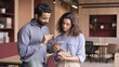 © insta_photos - Indian manager holding digital tablet having discussion with latin employee meeting in office lobby. Two diverse professionals talking using pad discussing project strategy, checking corporate plan.