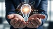 © mikael - Innovation and new idea concept. An entrepreneur's cupped hands hold a single, glowing holographic lightbulb, symbolizing a new idea.