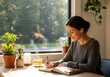 © artpixel - Woman writing in a notebook near a window with plants and sunlight