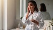 © Oleksandr - Woman in white robe apply cream on her face, enjoy morning skincare routine at home, female use moisturizing lotion for healthy radiant skin in bathroom