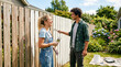 © Cliff - Happy young couple painting wooden fence together in sunny yard, DIY home improvement concept, smiling man and woman working outdoors on summer day