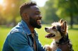 © miss irine - Smiling man in denim jacket holds small dog in green park. Sunny day creates happy mood and shows friendship between owner and pet. They enjoy time outdoors together.