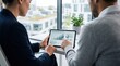© Haruto - Two business professionals analyzing renewable energy project ROI charts on a tablet computer in a bright office setting, discussing sustainability investment and green technology