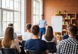 © twilight mist - Professional man gives a presentation to a diverse group of students in a bright loft office.