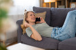 © Dexon Dee - Woman smiling relaxing on sofa making phone call