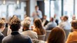 © Oleh - Diverse group of professionals attending a corporate seminar, with a speaker presenting in the blurred background, focusing on concepts of education, learning, and communication