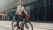 © Lamia - Smiling man in casual business attire riding a modern bicycle with a leather bag through a contemporary city street, enjoying his commute