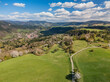 © AmazingAerialAgency - Aerial view of the Sajbica area near Lubietova with rolling green hills, blooming spring trees and a winding dirt path under a blue sky, Lubietova, Banska Bystrica Region, Slovakia.
