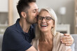 © fizkes - Close up shot loving grown up adult son cuddling and kissing his older happy mom, seated on sofa at home. Family spend priceless time together, enjoy good and harmonic relations between two gen people