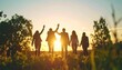© Yohan - Silhouetted people embrace golden hour, holding hands, arms raised to celebrate the sun's descent. They stand in a field