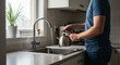 © Ksenia - Man filling kettle at sink from high angle with tea bags and cups nearby
