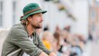 © Pinklife - A thoughtful man wearing a green hat and casual attire gazes off into the distance amidst a dynamic and lively backdrop of urban life and social interactions.