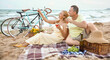 © Pixel-Shot - Mature couple having picnic near sea on summer day