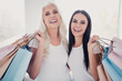 © deagreez - Mother and daughter smiling with shopping bags after a day of retail therapy, happy women enjoying fashion and time together