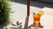 © Pram - A refreshing glass of iced tea with lemon sits on a wooden table outdoors in sunlight.