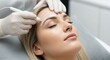 © siam - Professional aesthetician performing a brow mapping procedure on a clients forehead in a beauty clinic