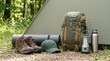 © spyrakot - Neatly packed summer camping gear arranged outside tent in forest