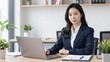 © Studicon - Confident asian businesswoman working on laptop at desk in bright office setting